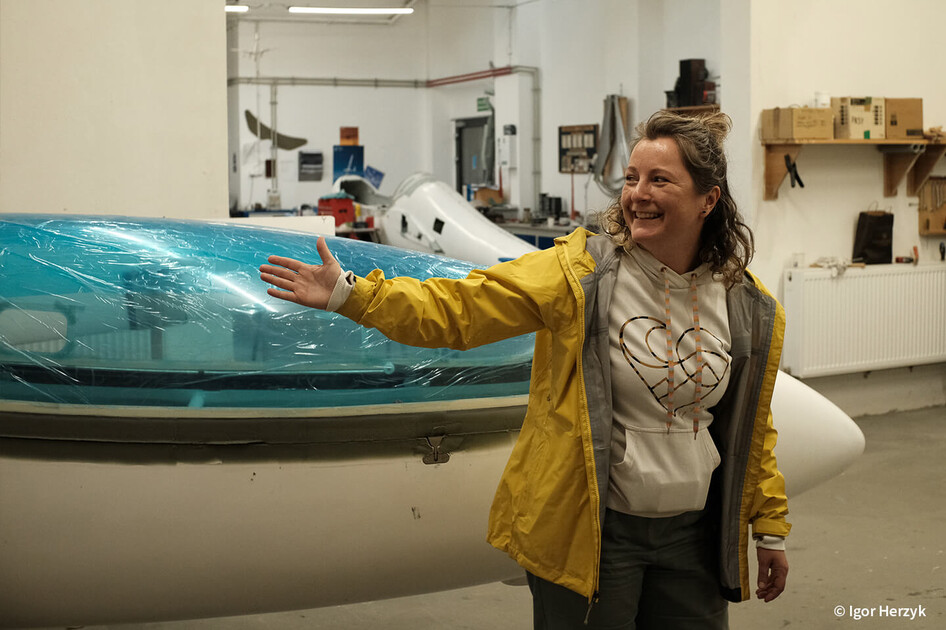 Besucherin bei der Museumsnacht erklärt vor einem Segelflugzeug, Aufnahme in Farbe.